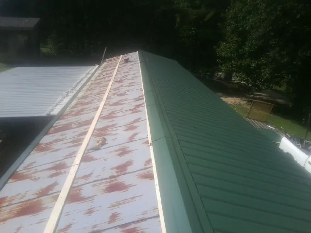 Old rusted panels beside newly installed green metal roofing — Wind Damage Roof Repair by Roofing Brothers in Oak Park