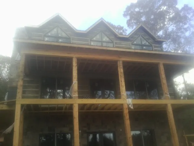 Dormers and porch framing on a large log home under construction — Roof Coating work by our crew in Oak Park